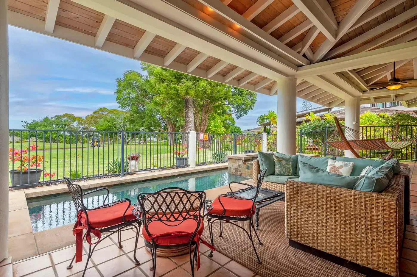A patio with chairs and a pool in the background.