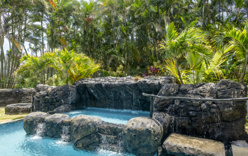 Tropical oasis with waterfall and lush greenery.