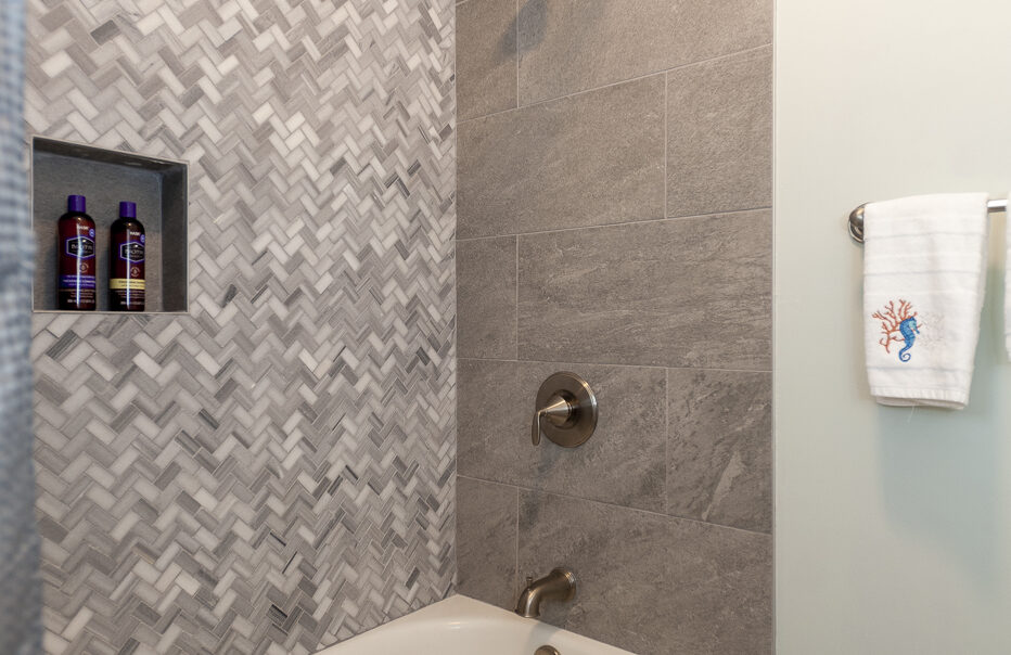 Modern shower with herringbone tile and tub.