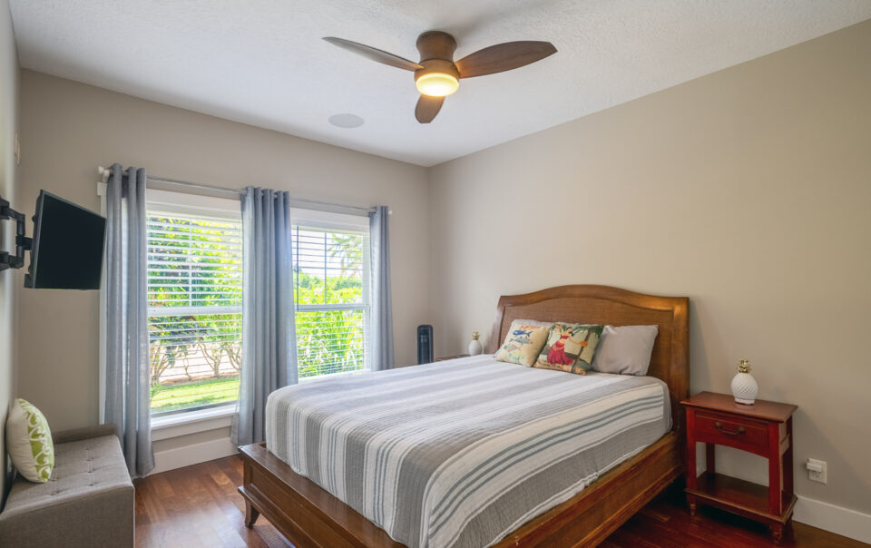Bright bedroom with wooden bed and TV.