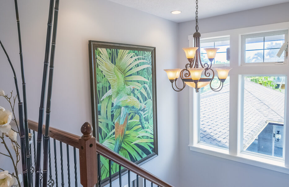 Staircase with tropical artwork and chandelier.
