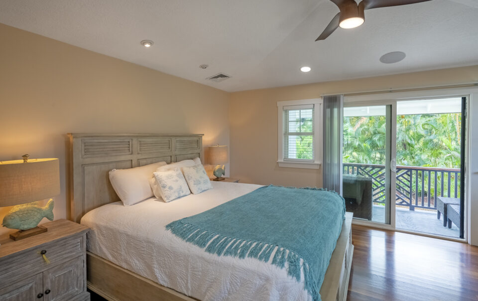 Bright bedroom with tropical decor and balcony.