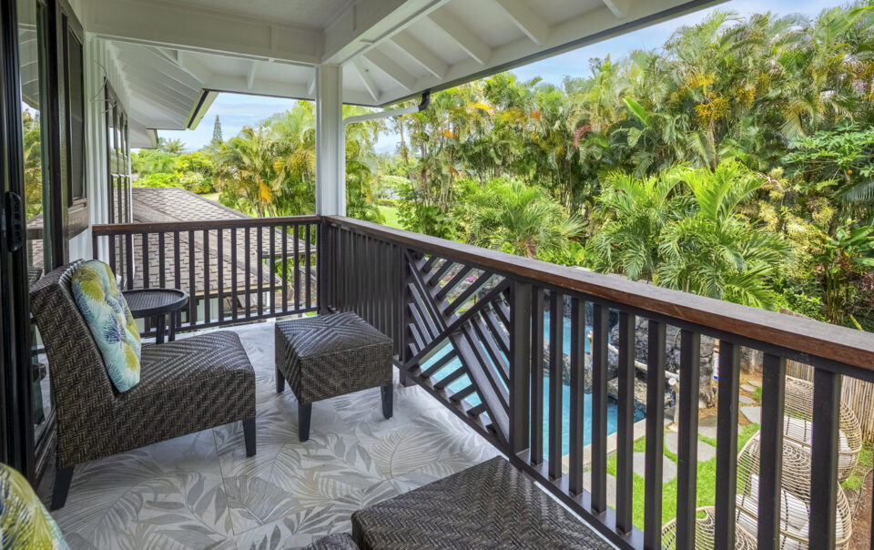 Tropical balcony with seating and lush views.