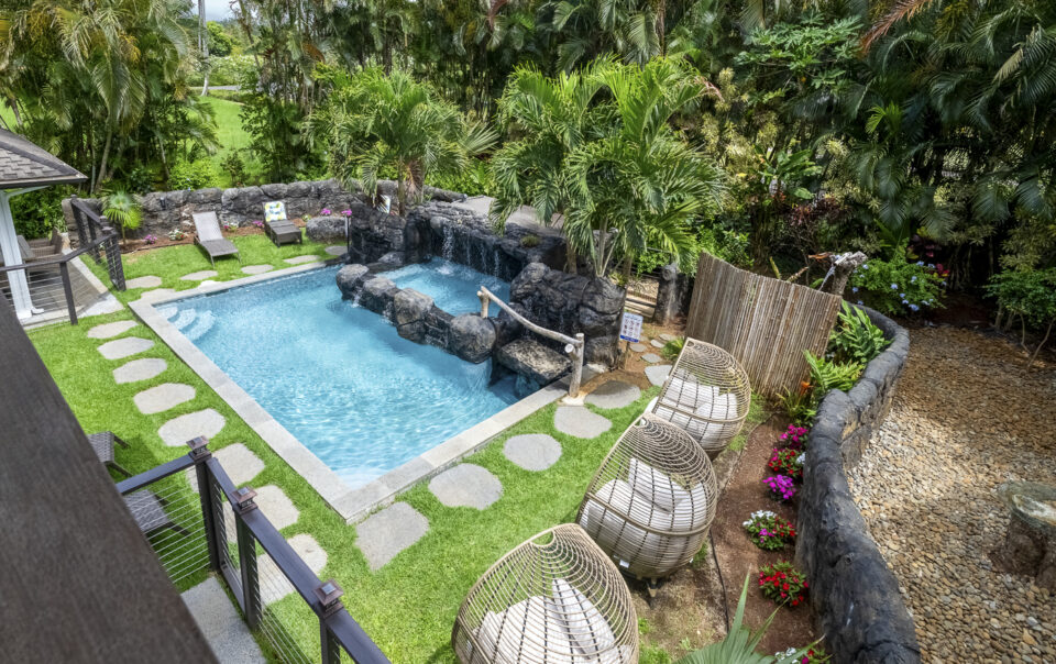 Tropical pool area with waterfall and seating.